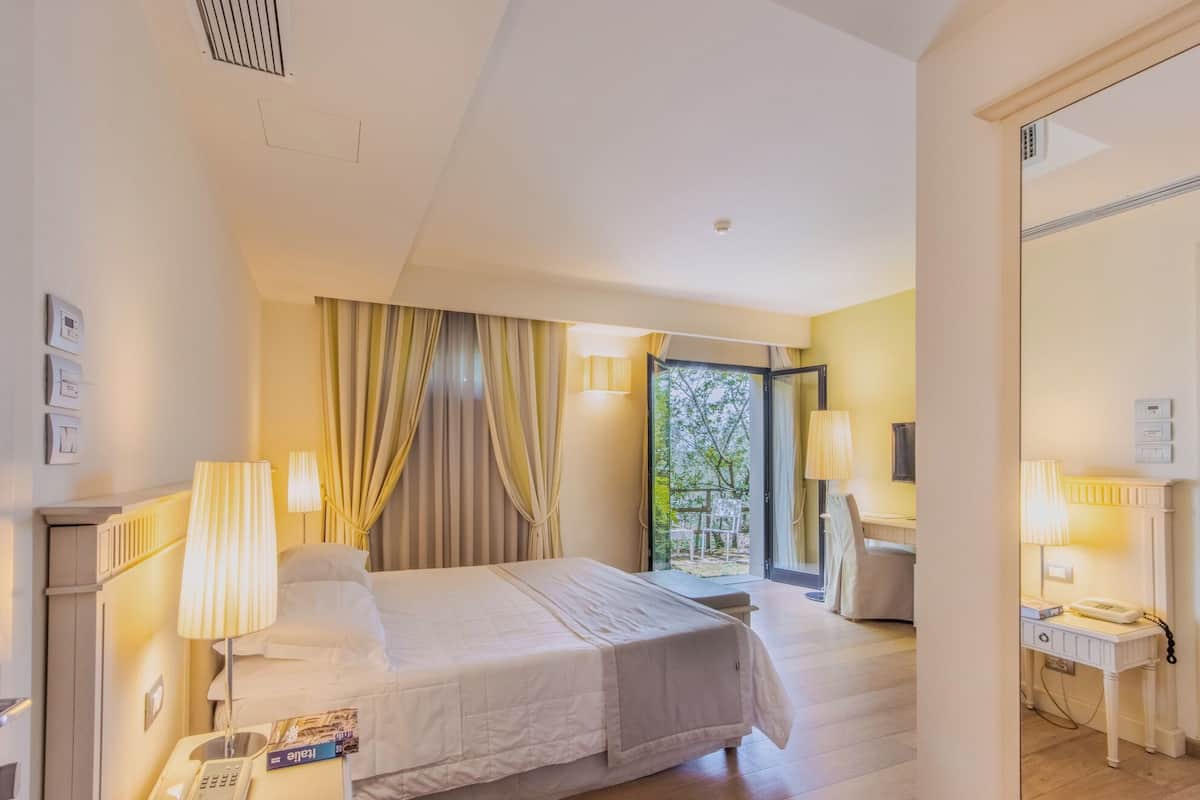 Une chambre d’hôtel avec un lit, des lampes de chevet, un téléphone et une vue sur l’extérieur.
