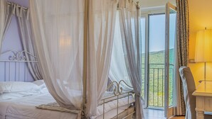 Une chambre à coucher avec un lit à baldaquin, un balcon avec vue et une table de chevet avec une lampe.