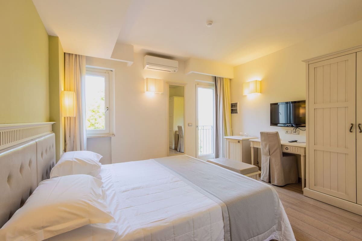 Une chambre d’hôtel comprenant un lit, un bureau avec une chaise, une télévision et une armoire.