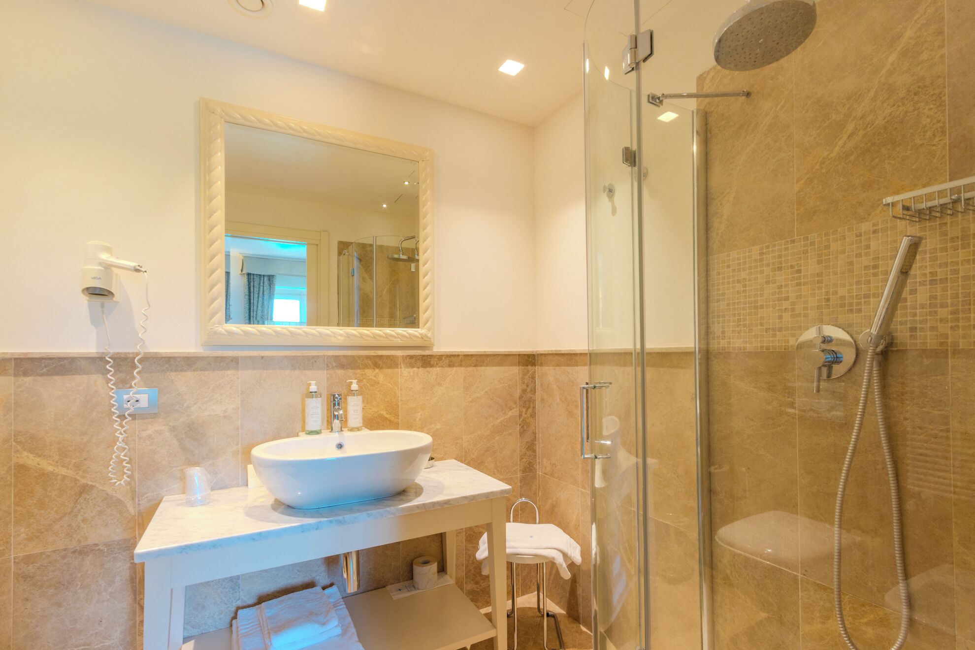 Un bagno moderno con uno specchio grande, un lavandino, una doccia e un asciugacapelli.