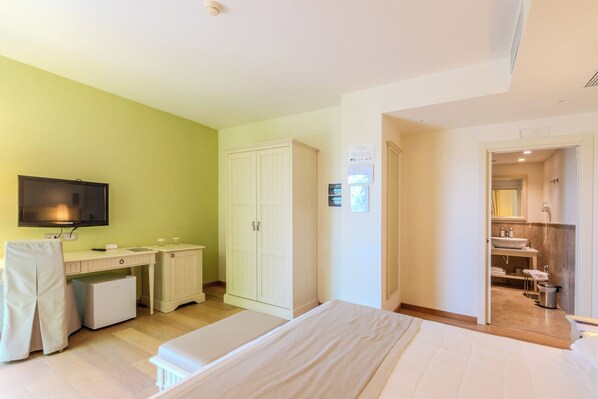 A bedroom with a bed, a television, a desk, and a wardrobe.