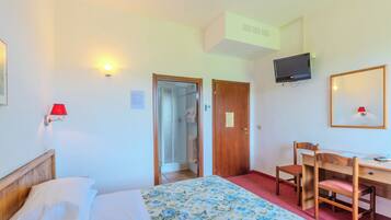Ein Hotelzimmer mit Bett, Schreibtisch, Stuhl, Fernseher und Dusche.