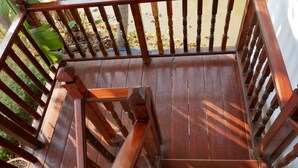 A wooden staircase with a railing leading to a deck area.