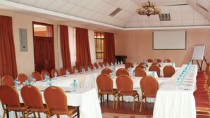 Ein Konferenzraum mit langen Tischen, Stühlen und einer Projektionsleinwand.