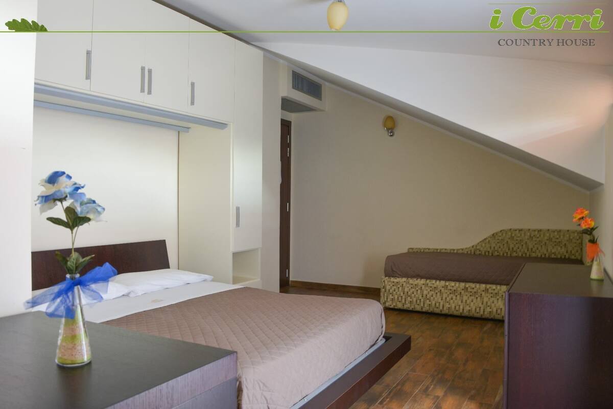 A bedroom with a bed, a nightstand, a dresser, and a window.