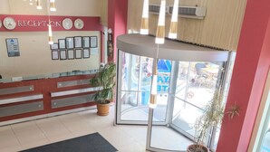 A hotel reception area with a reception desk, seating area, and a large window. - Siyav Hotel (Ankara)