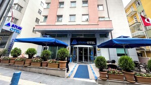 A hotel with a modern facade, multiple balconies, and a blue entrance canopy. - Siyav Hotel (Ankara)