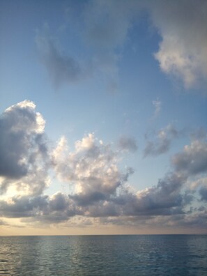 Cielo despejado con algunas nubes sobre un mar tranquilo.