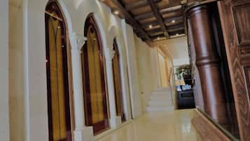 A hallway with arched windows and a polished floor leading to a staircase.