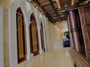 A hallway with arched windows and a polished floor leading to a staircase. - La PLace Hotel (Zahlé)