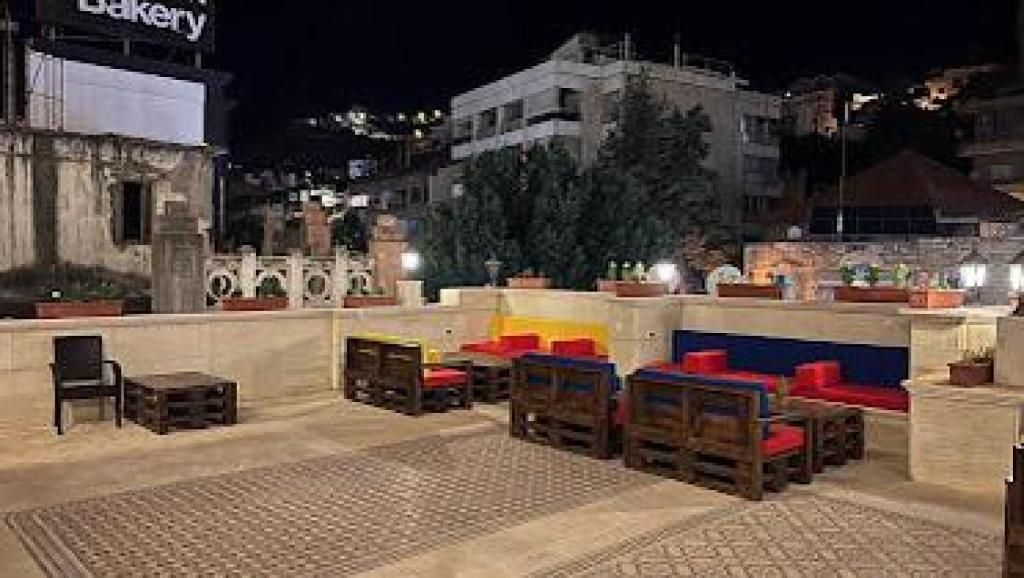 An outdoor seating area with wooden furniture and a stone wall backdrop.