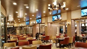 A spacious restaurant with multiple dining areas, each featuring tables and chairs. - La PLace Hotel (Zahlé)