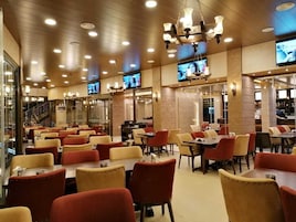 A spacious restaurant with multiple dining areas, each featuring tables and chairs.