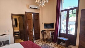 A hotel room with a bed, a desk, a TV, and a large window. - La PLace Hotel (Zahlé)