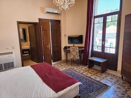 A hotel room with a bed, a desk, a TV, and a large window.