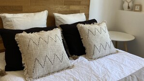 A neatly made bed with white and black bedding, a wooden headboard, and decorative pillows. - Mas Lafleur (Chateaurenard)