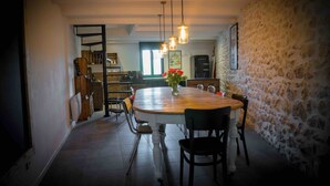 A dining area with a round wooden table, chairs, and hanging pendant lights. - Mas Lafleur (Chateaurenard)