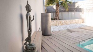 A statue of a figure on a wooden deck next to a swimming pool. - Mas Lafleur (Chateaurenard)