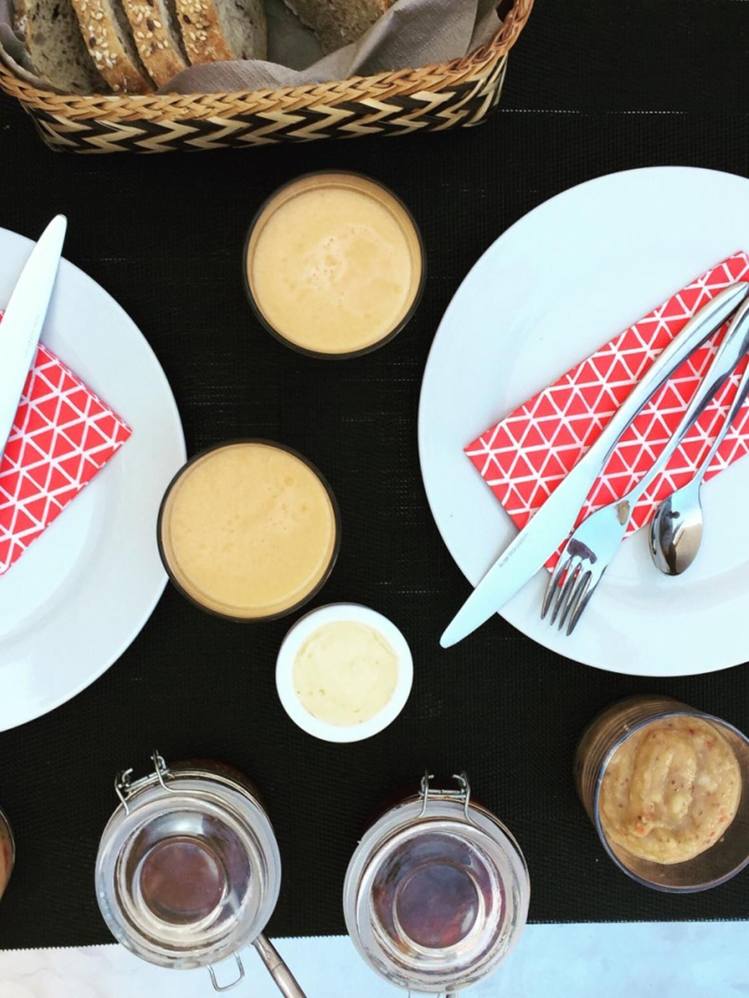 Une table dressée avec des assiettes, des bols et des pots, qui contiennent probablement de la nourriture et des condiments.
