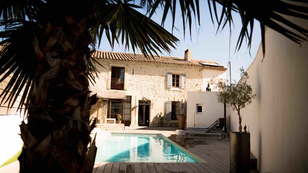 A stone building with a pool, surrounded by palm trees and a small garden. - Mas Lafleur (Chateaurenard)
