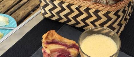 A table with a slice of pie, a glass of coffee, a basket of bread, and a bowl of granola.