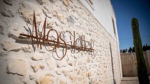 A stone wall with a metal sign spelling "Wes Holloway." - Mas Lafleur (Chateaurenard)