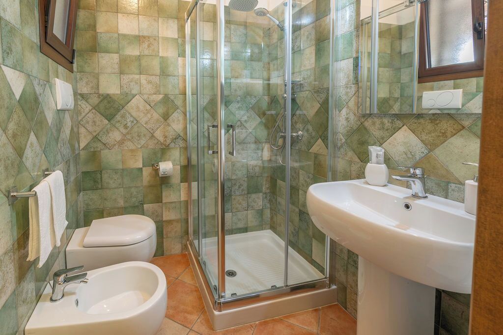A bathroom with a glass-enclosed shower, a bidet, a sink, and a toilet.