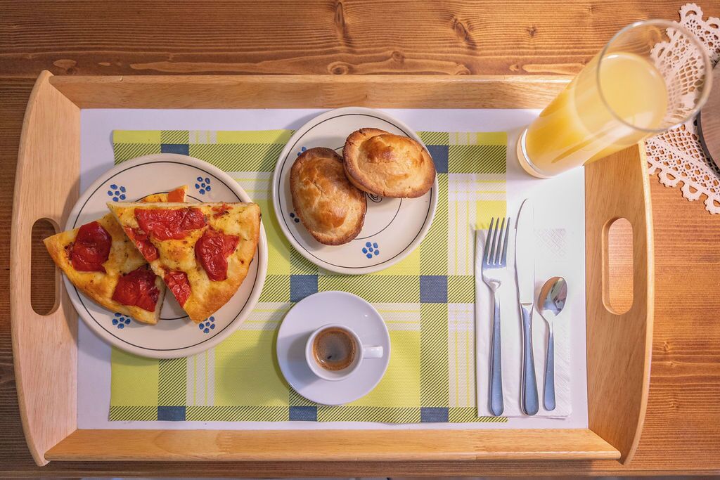 Ein Frühstücksbrett mit Pizza, Keksen, einer Tasse Kaffee und einem Glas Orangensaft.