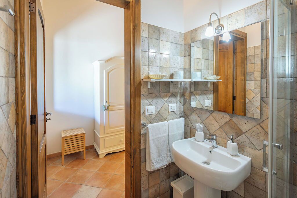 A bathroom with a sink, mirror, and shelves with toiletries.