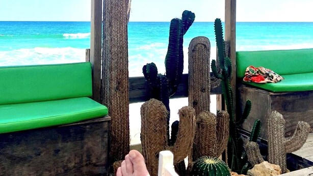 A wooden deck with a view of the ocean, featuring green seating and cacti. - Zenit Guest House (Olhao)