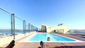 A rooftop pool with a clear view of the sea, a glass balustrade, and a lounge area with a chair. - Zenit Guest House (Olhao)