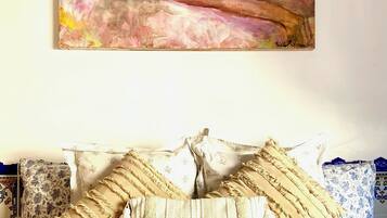 Un dormitorio con cama, ropa de cama estampada con motivos florales y un cuadro sobre la cama.