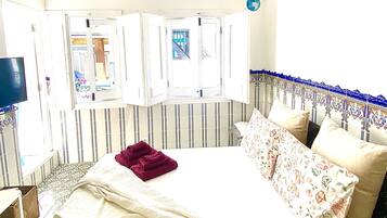 A bedroom with a bed, a window, and a television.