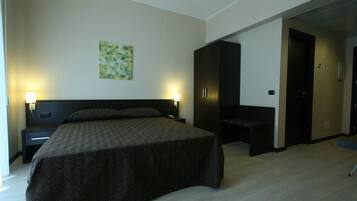 A hotel room with a large bed, two bedside tables with lamps, a wardrobe, and a painting on the wall.