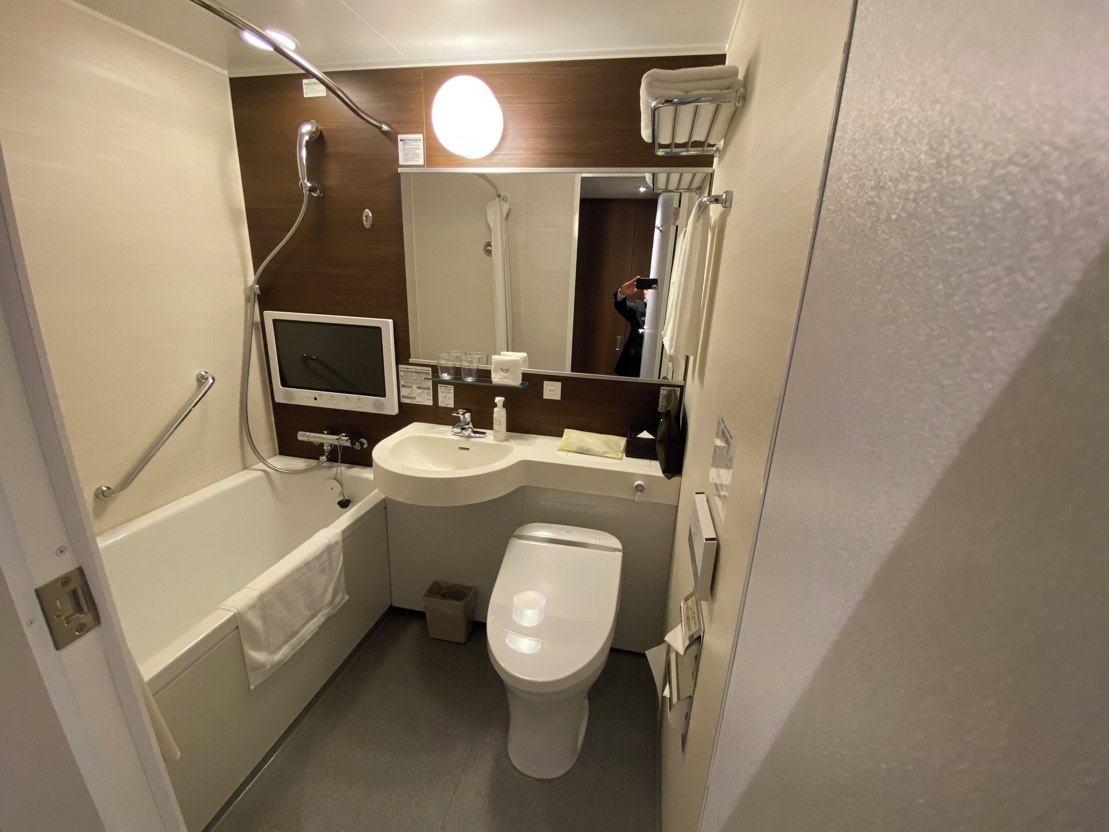 A compact bathroom with a bathtub, a sink, a toilet, and a mirror.