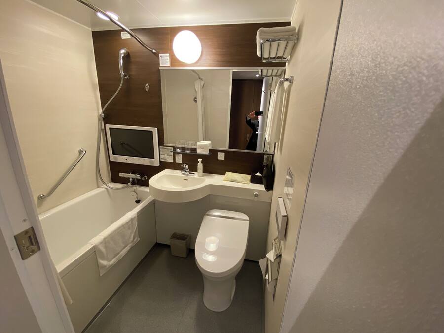 A compact bathroom with a bathtub, a sink, a toilet, and a mirror.
