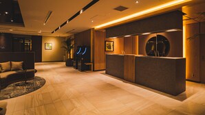 A modern reception area with a reception desk, seating area, and a large potted plant. - Hotel Grand View Takasaki (Takasaki)