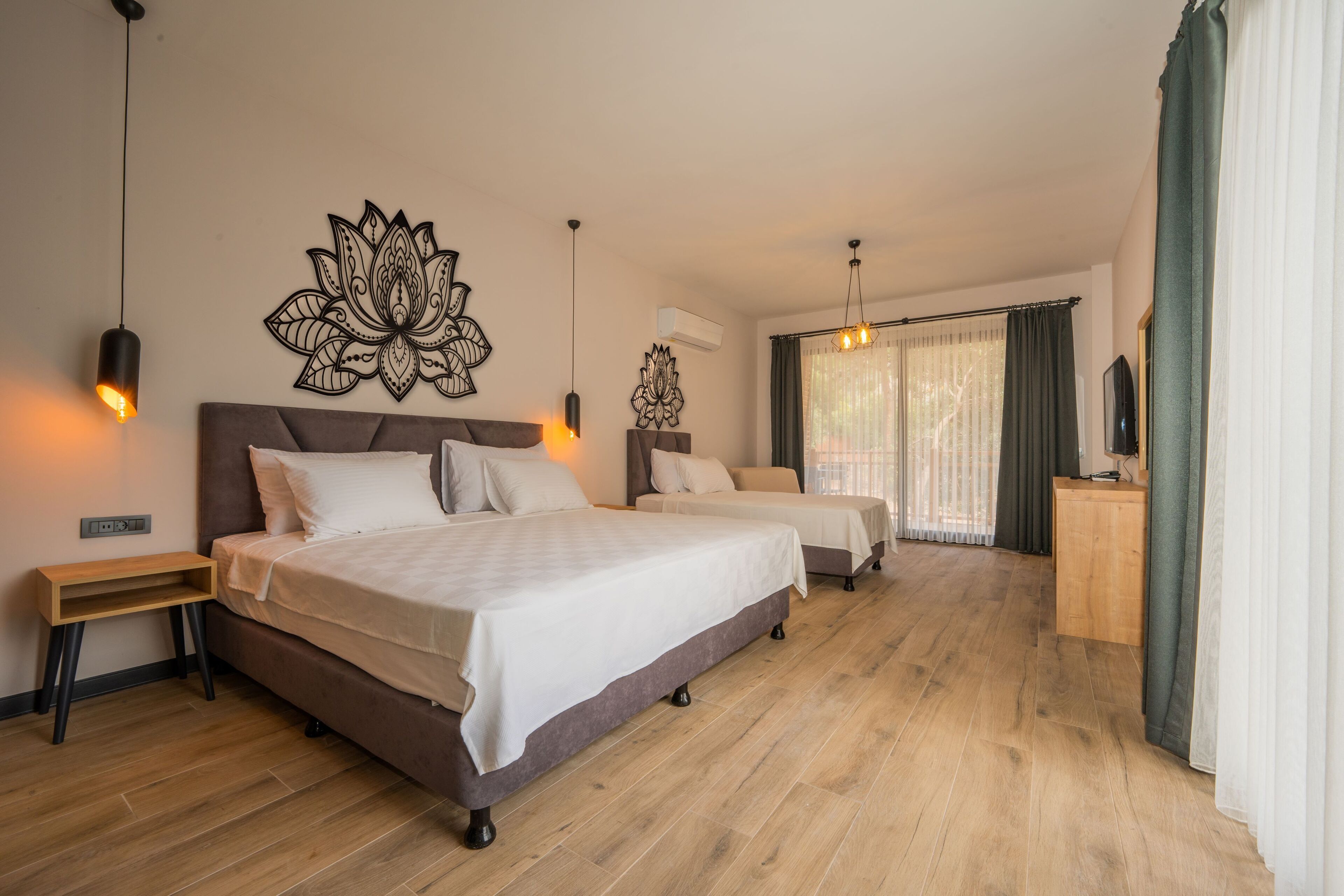 A modern hotel room with two beds, a wooden floor, a large wall art piece, and a desk with a TV.