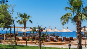 A beachside lounge area with wooden lounge chairs and thatched umbrellas, overlooking the sea. - Sea Valley Lodge (Fethiye)