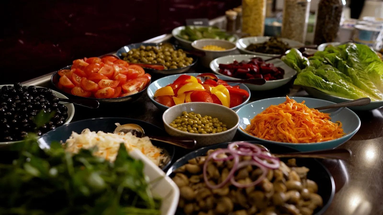 A variety of food items arranged on a table, including tomatoes, olives, carrots, and other vegetables.