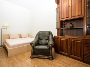 Simple, stylish space with a single bed, armchair, and storage cabinet.