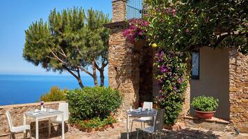 Una terraza con dos mesas dispuestas para comer, con vistas panorámicas al mar.