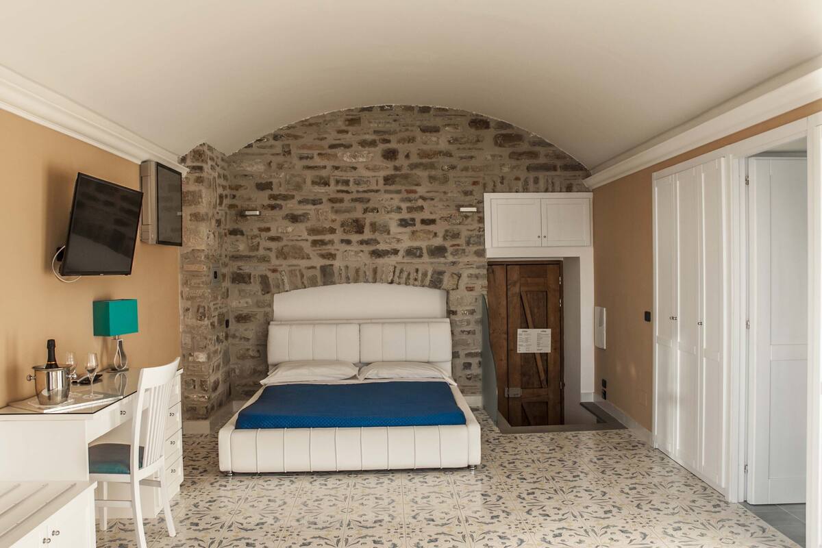 Ein Schlafzimmer mit Steinwand, einem Bett, einem Schreibtisch und einem Fernseher.