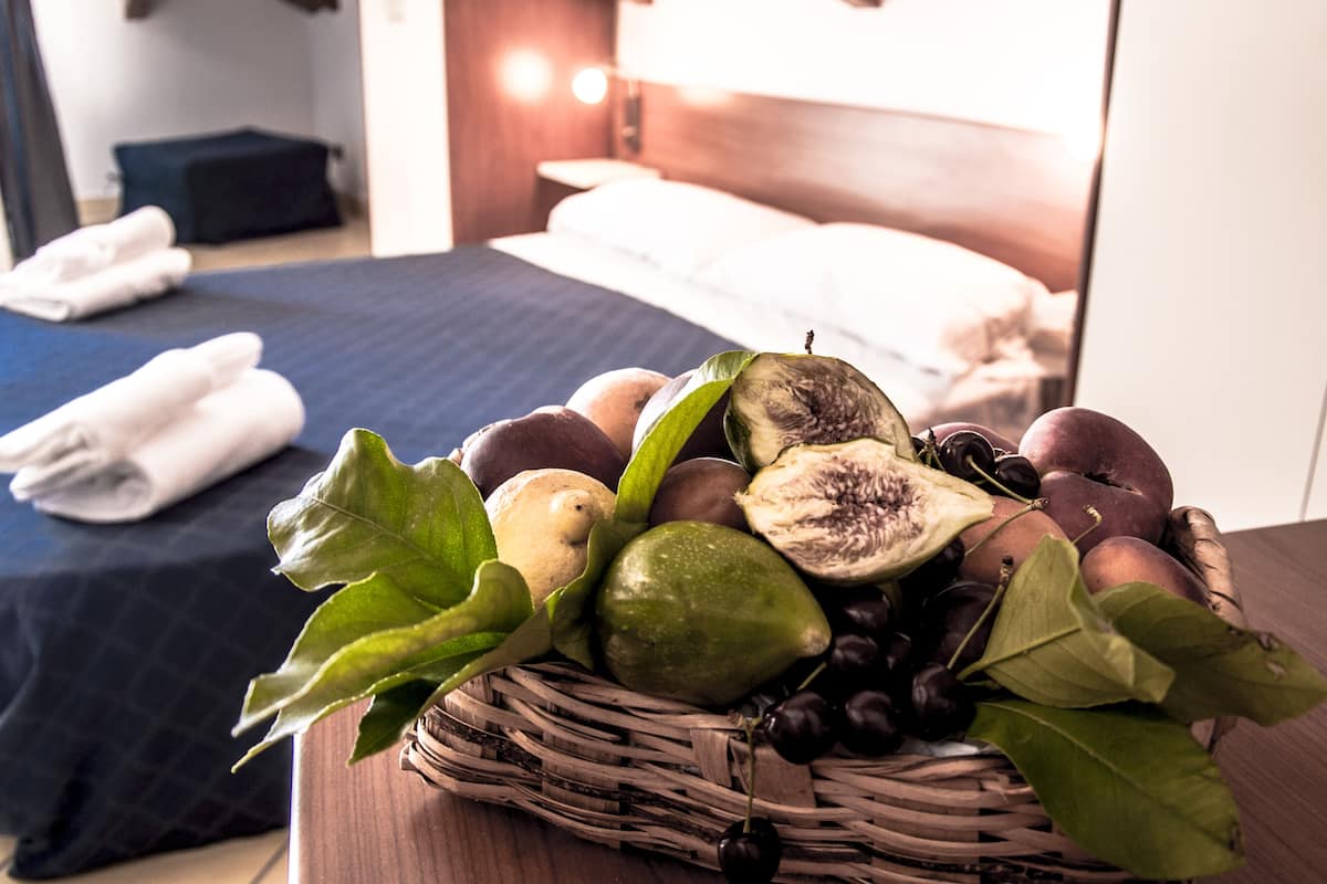 Ein Zimmer mit einem Bett, einer Obstkorb und einem ordentlich bezogenen Bett mit Handtüchern.