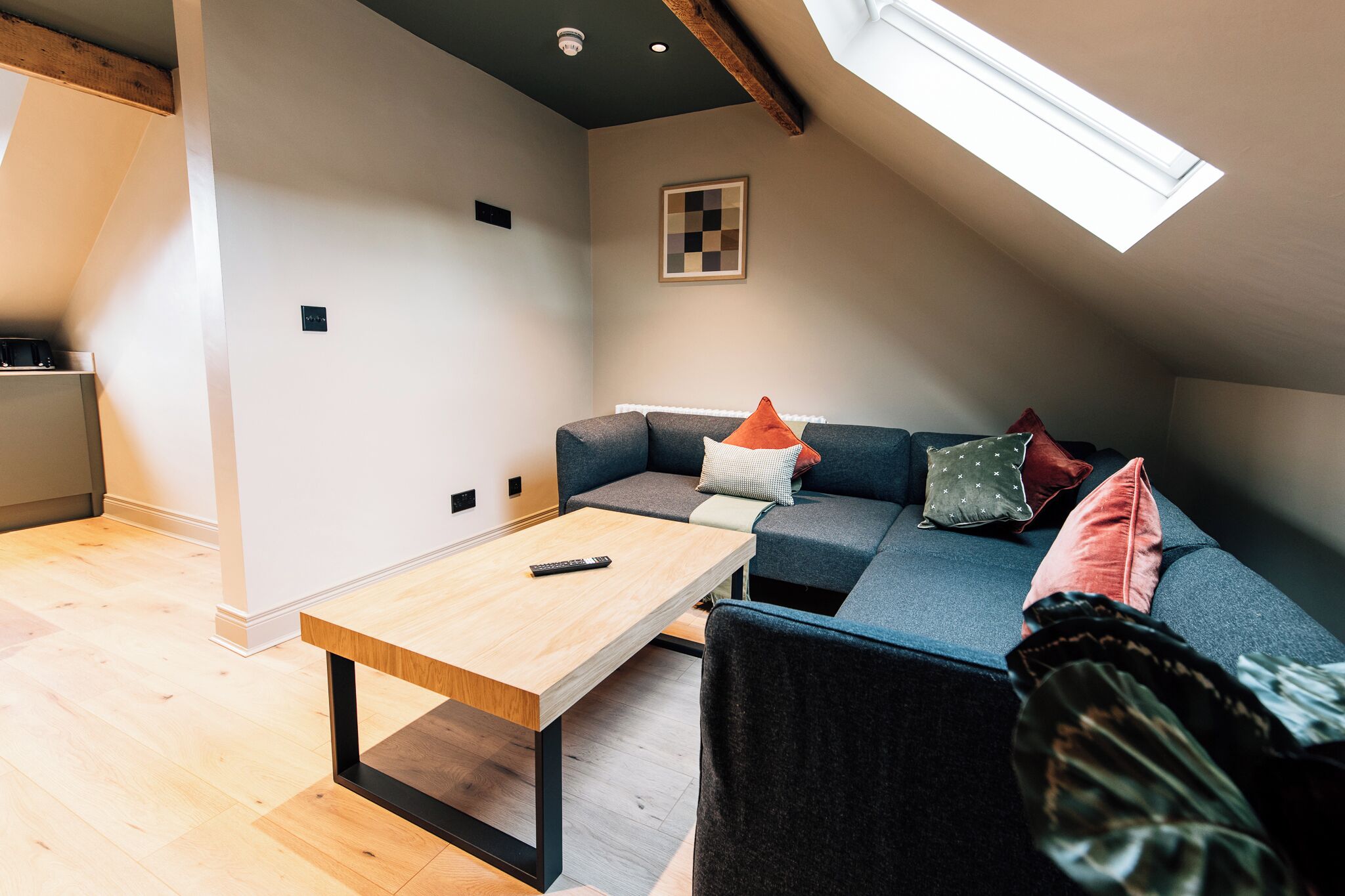 Una habitación moderna estilo loft con techo inclinado, un banco empotrado, un sofá y una pequeña mesa.