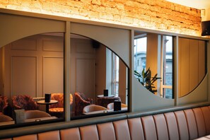 A restaurant with a brick wall, cushioned seating, and a view through a curved window. - The Nines, Bangor Marina (Bangor)