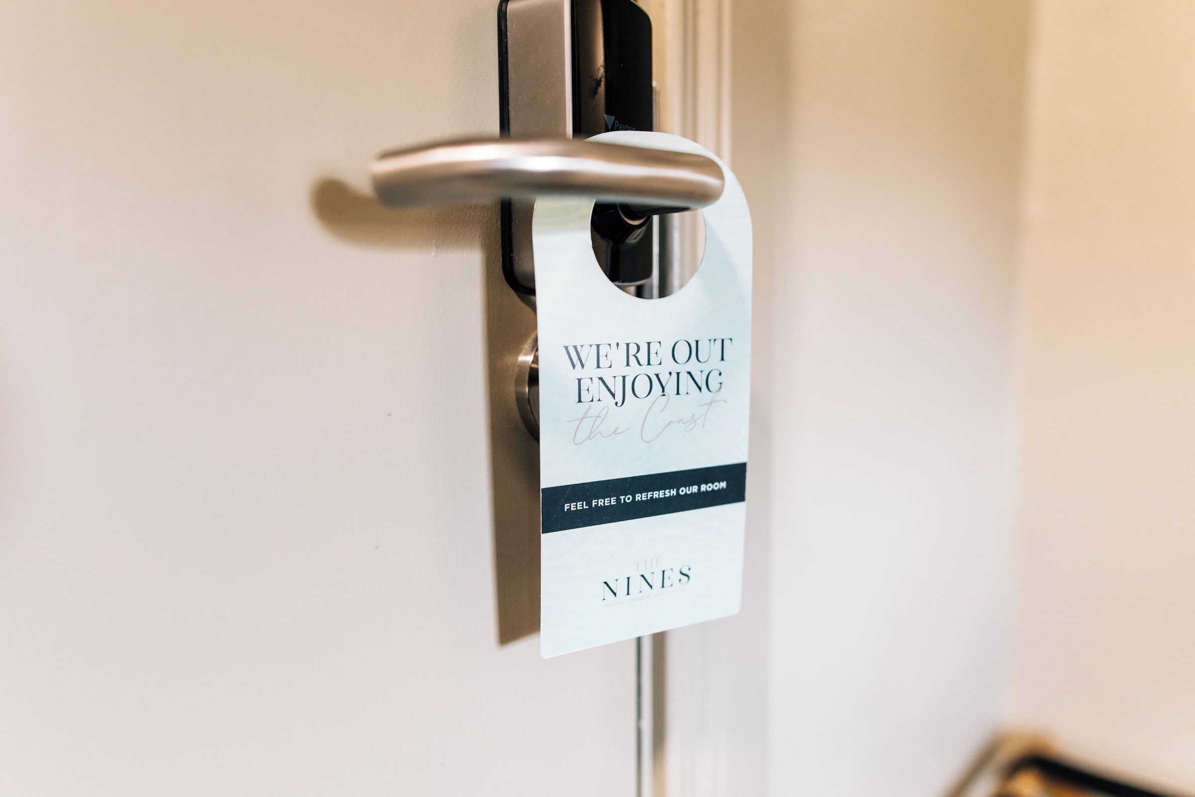 Une porte de chambre d’hôtel avec un panneau indiquant que la chambre est occupée et invitant les clients à demander le nettoyage de la chambre.