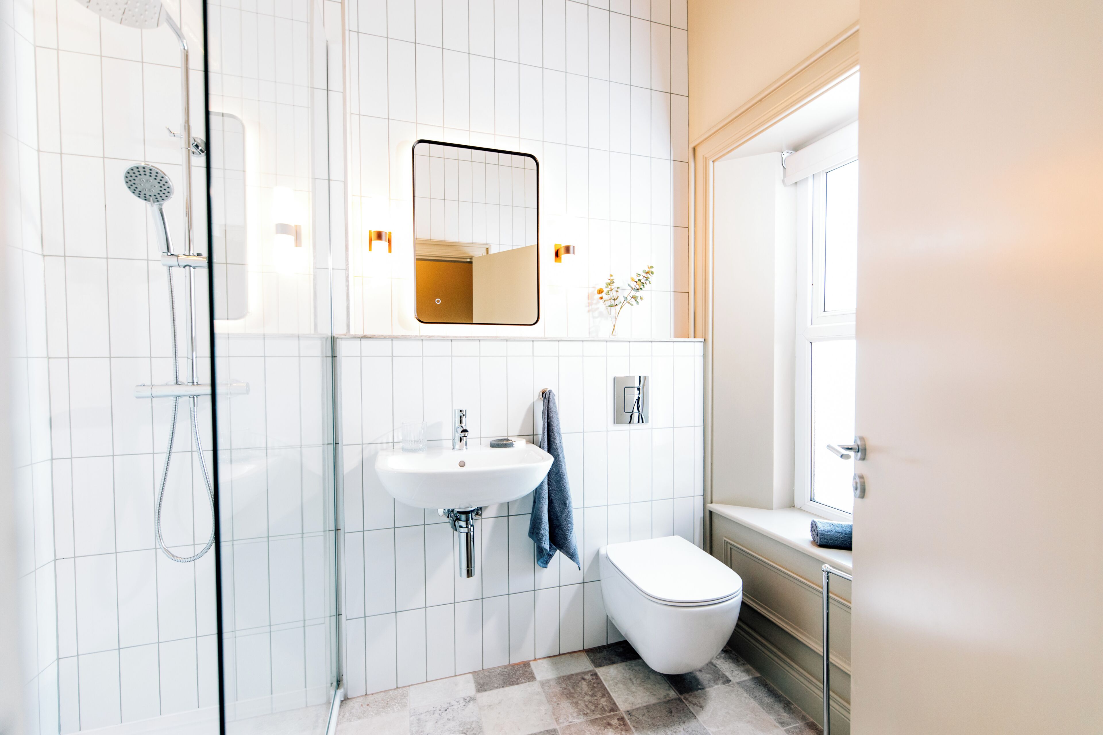 Un baño con ducha, lavamanos, inodoro y espejo.