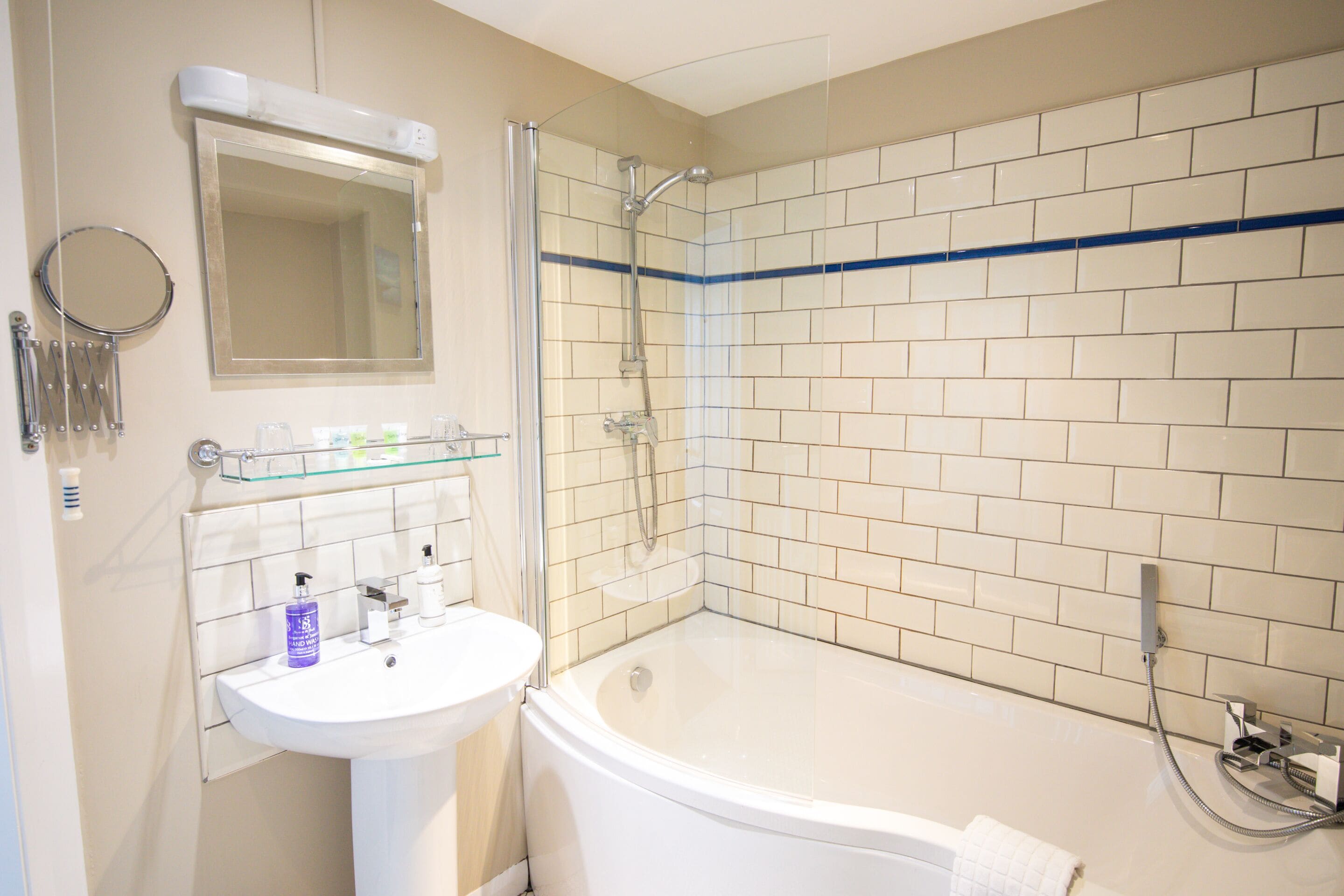 Een badkamer met een witte wastafel, spiegel en bad.