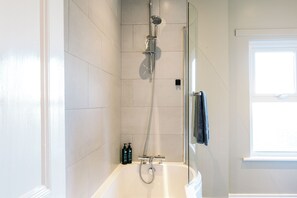 A modern bathroom with a glass-enclosed shower, a white bathtub, and a window providing natural light. - The Nines, Bangor Marina (Bangor)